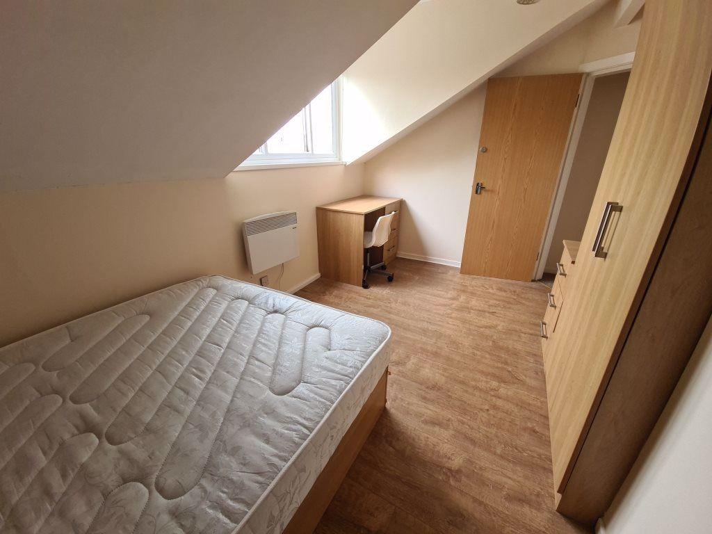 A cozy student bedroom featuring a double bed a...