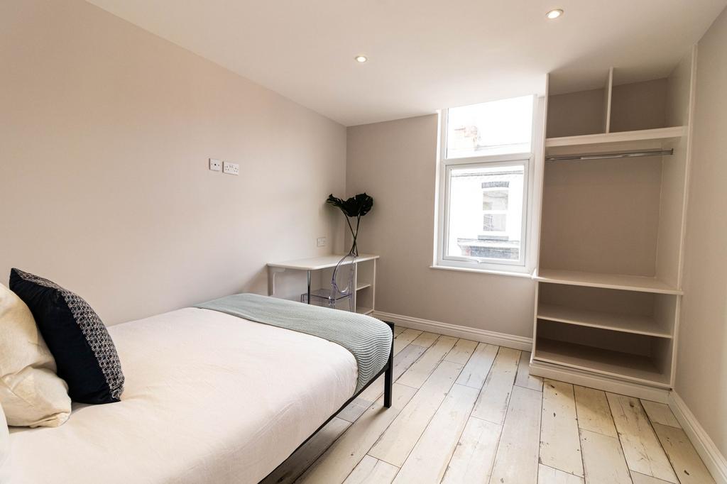 A bright and tidy single bedroom featuring a co...