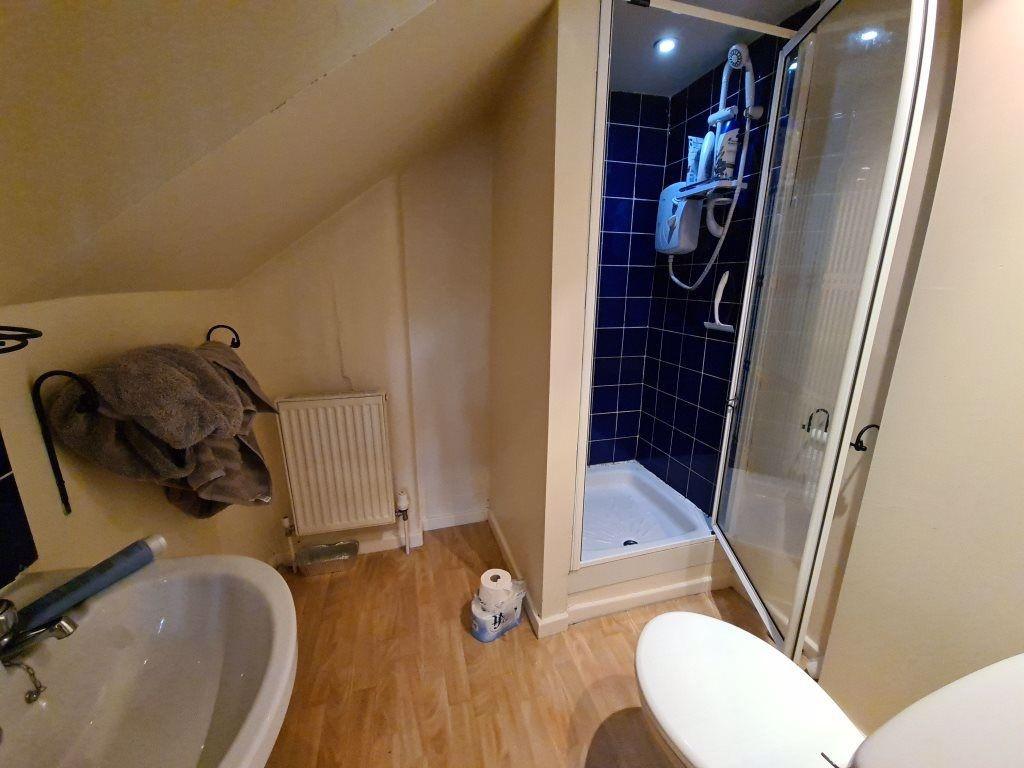 A compact bathroom featuring a corner shower wi...