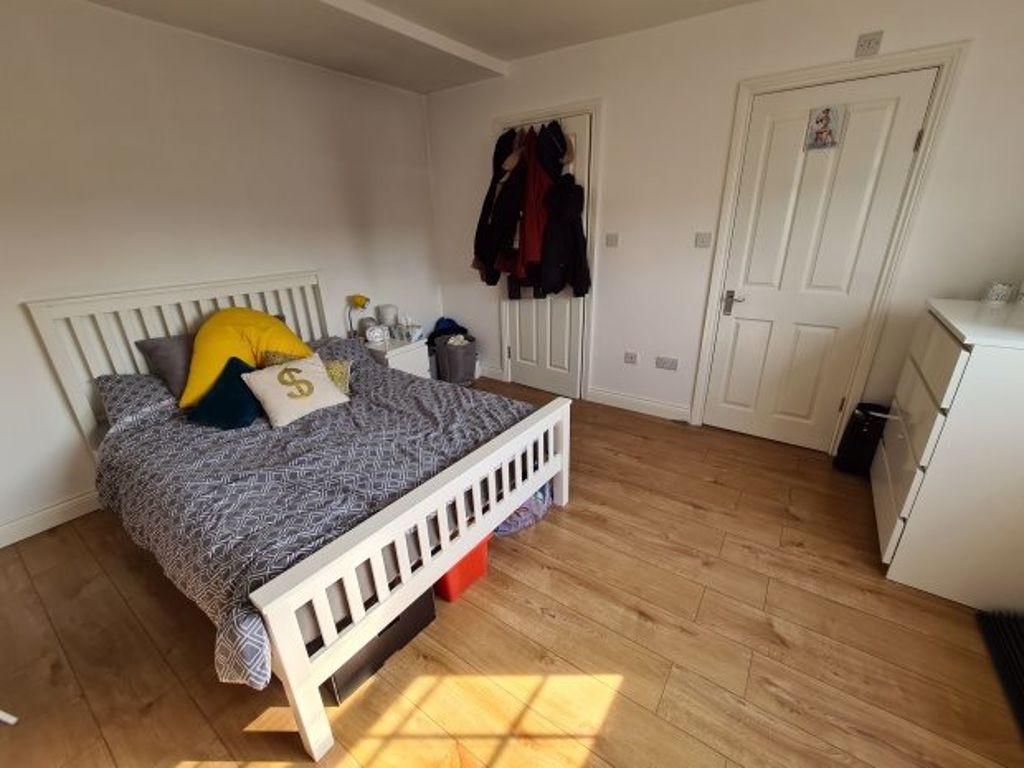 A bright and tidy bedroom featuring a white bed...