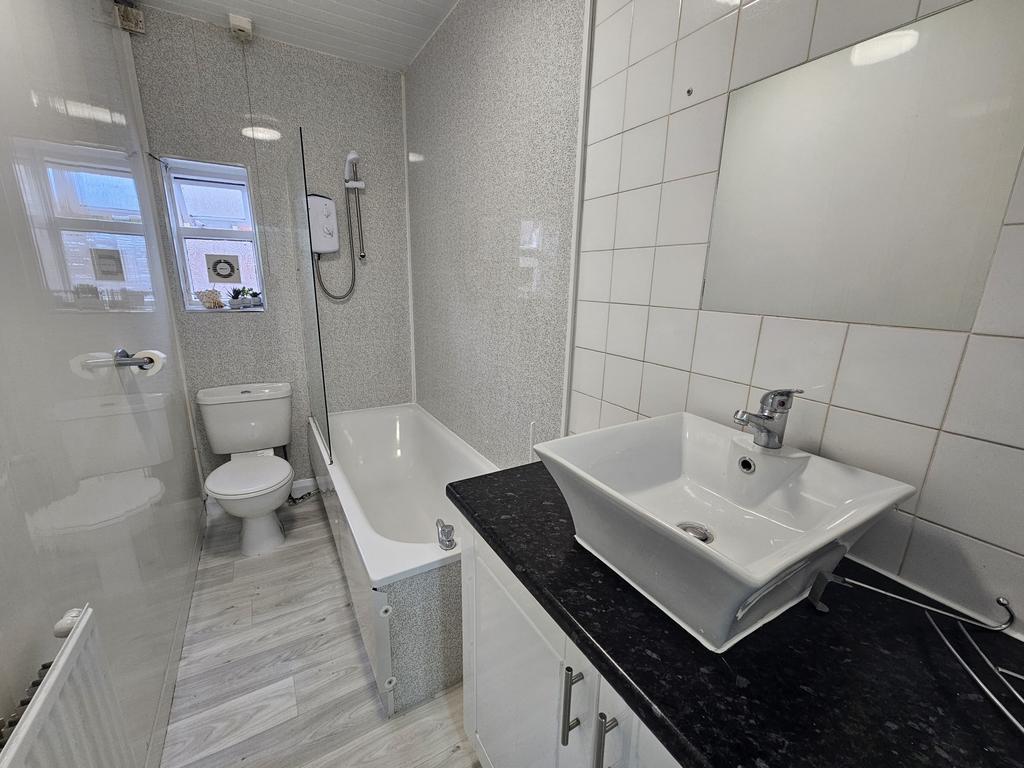 Modern shared bathroom with a white bathtub and...