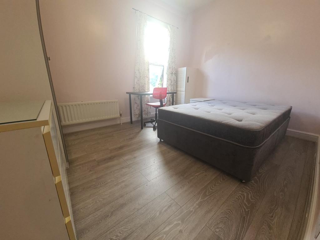 A spacious double bedroom with a comfortable be...