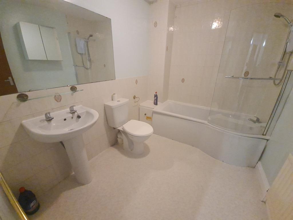 A clean and well-lit bathroom featuring a batht...
