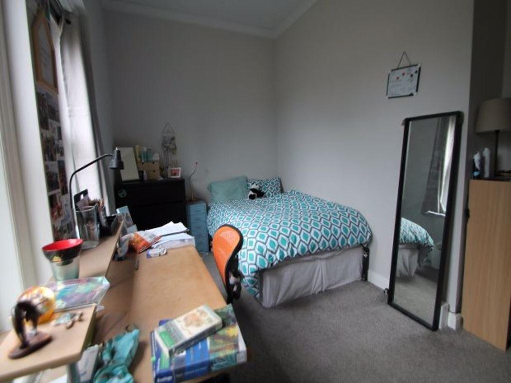 A cozy student bedroom featuring a bed with pat...