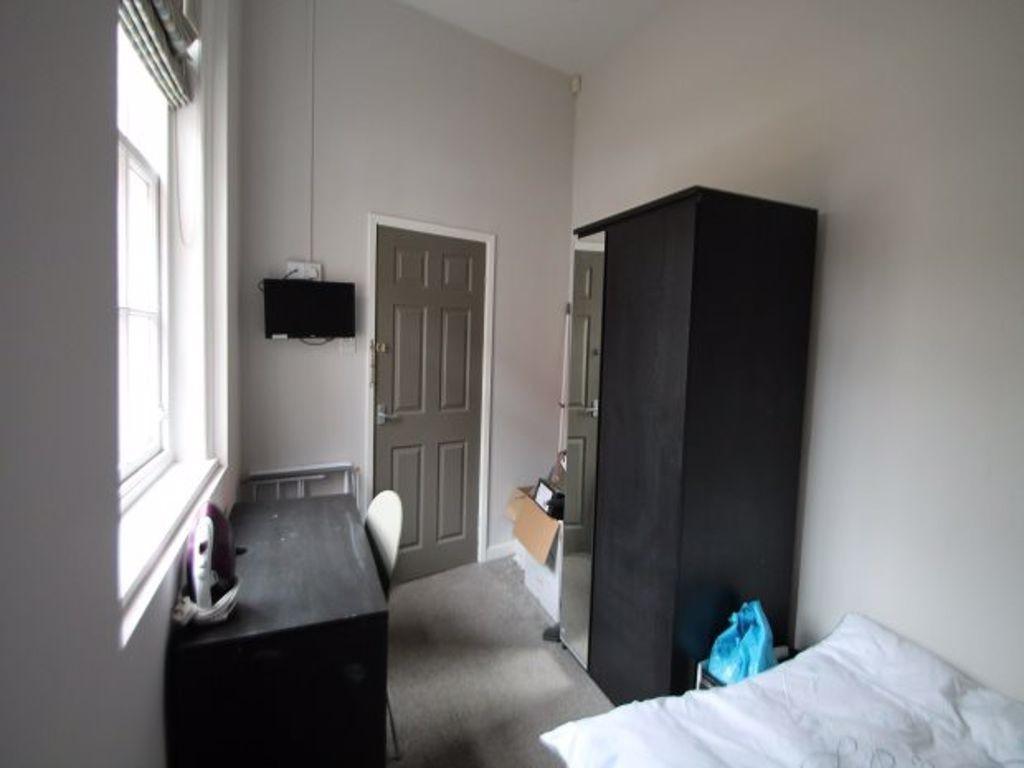 A tidy and well-lit student bedroom featuring a...