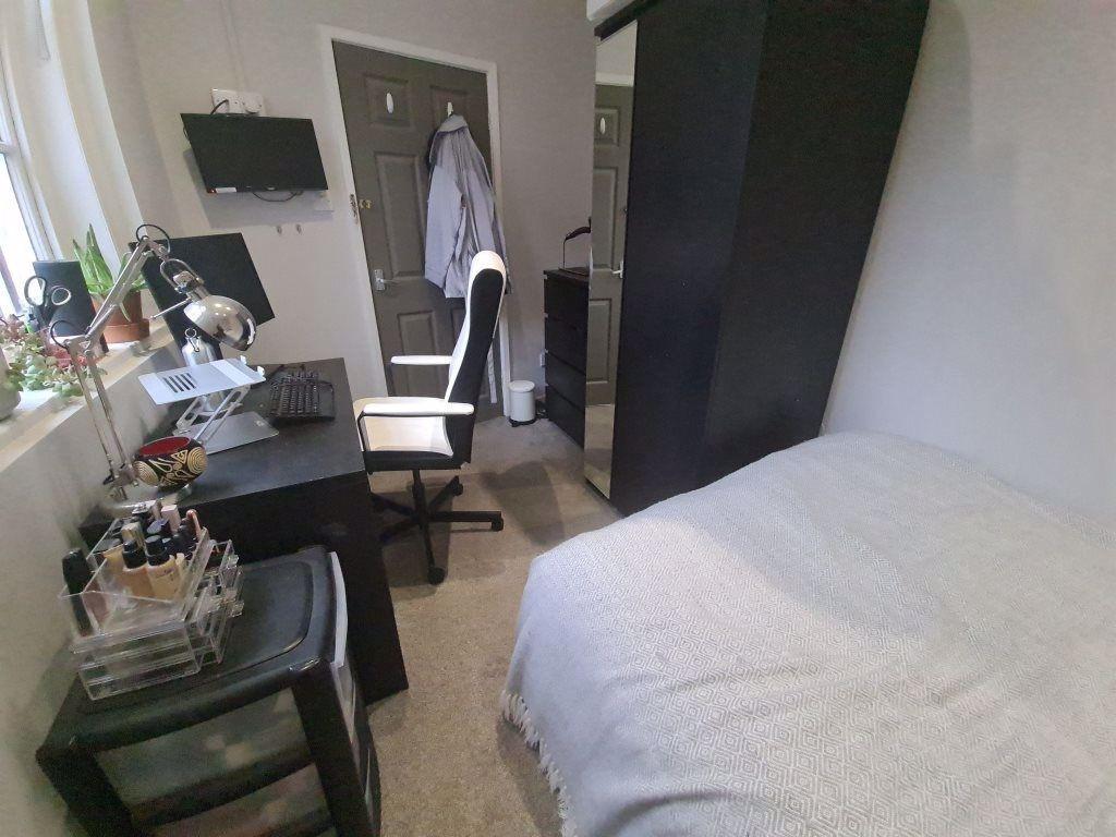 A cozy bedroom featuring a neatly made bed, wit...