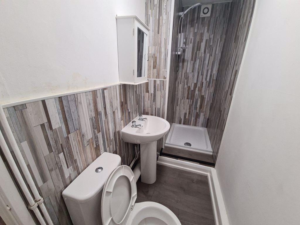 A clean, modern bathroom with a toilet, sink, a...