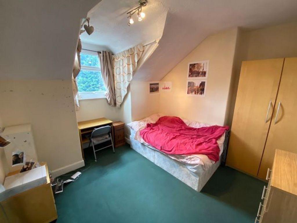 A cozy bedroom featuring a single bed with a br...