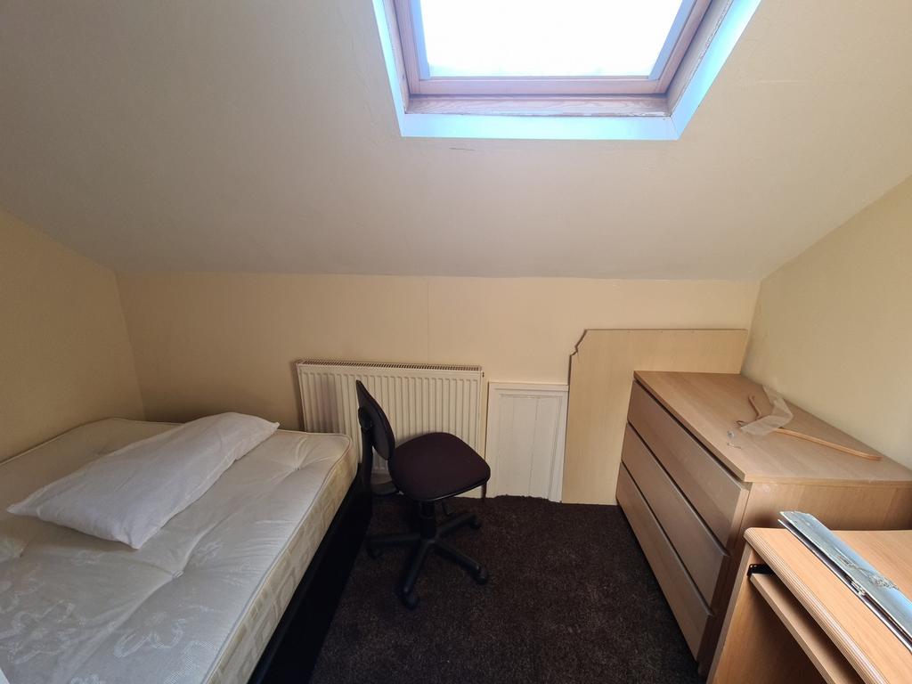 A cozy single bedroom featuring a bed, a small ...