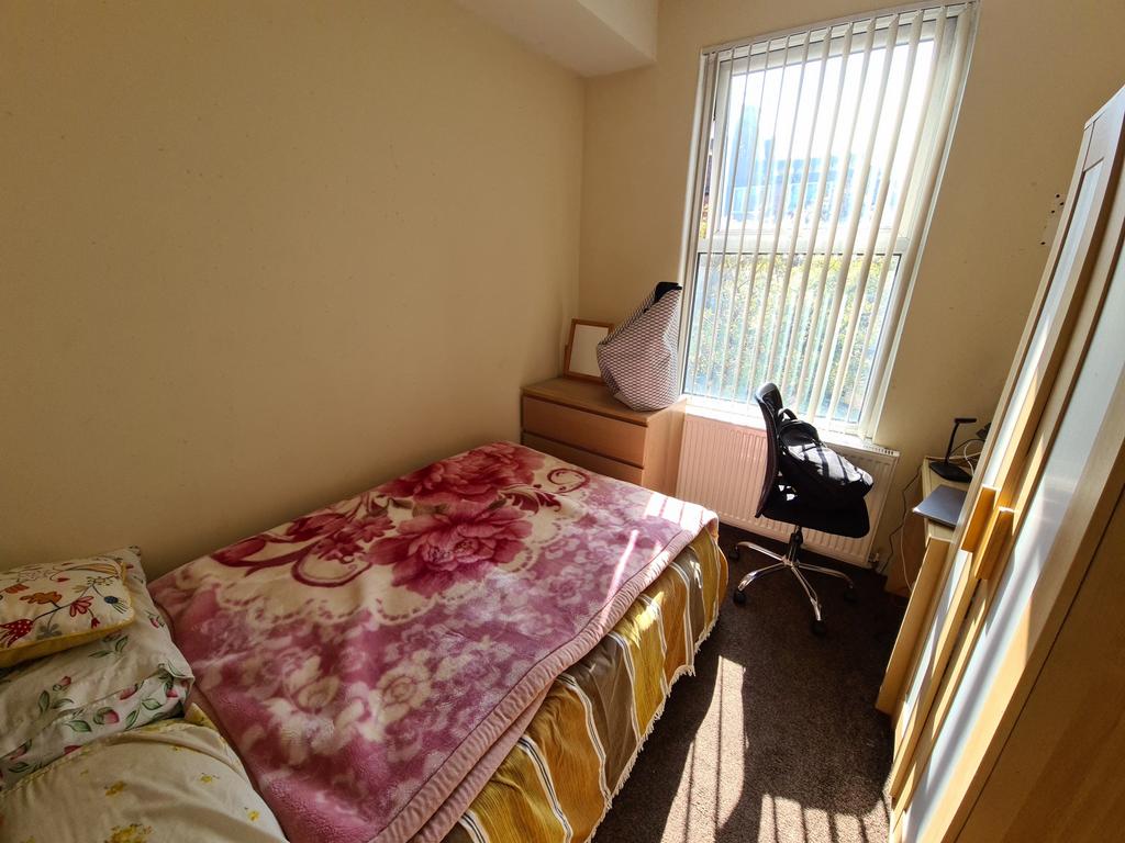 A cozy and well-lit single bedroom featuring a ...