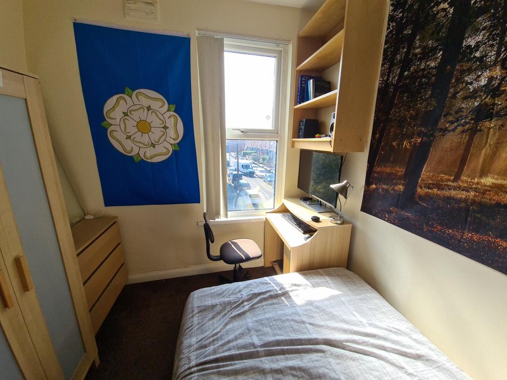 A cozy student bedroom bathed in natural light ...