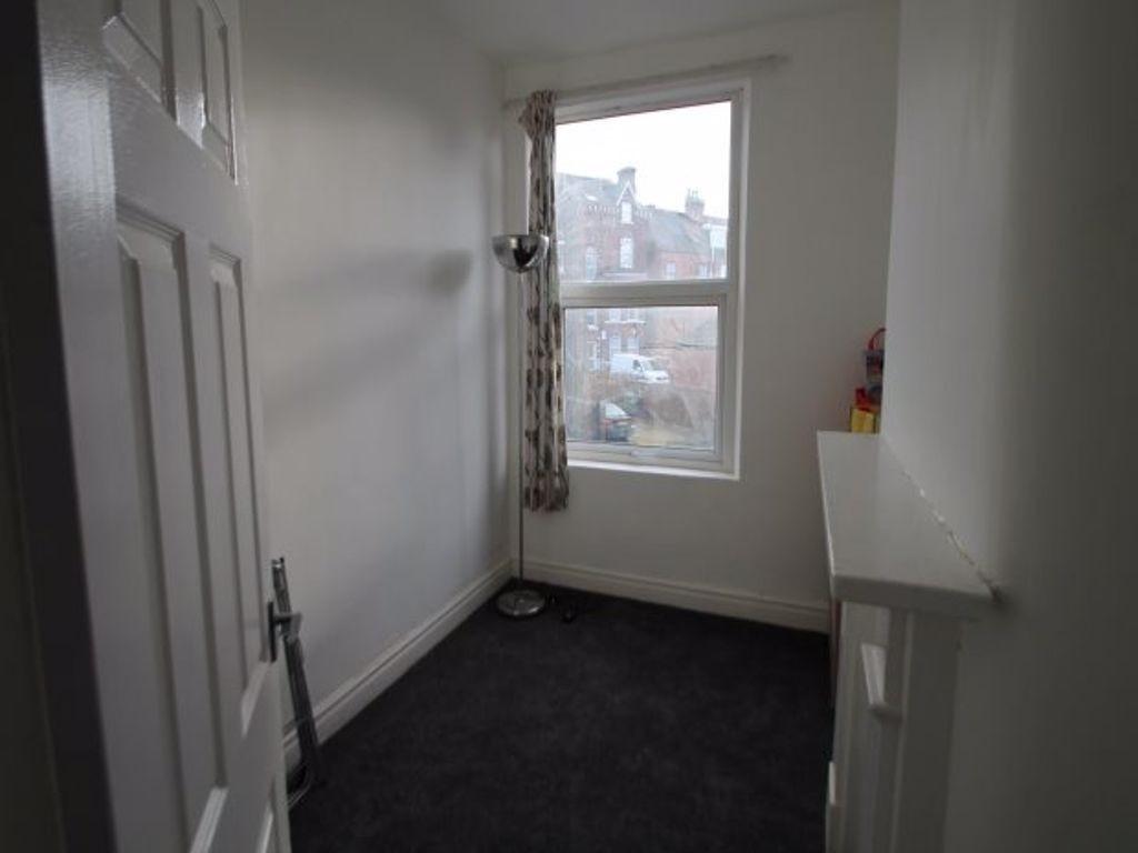 A small, simply furnished bedroom with a window...