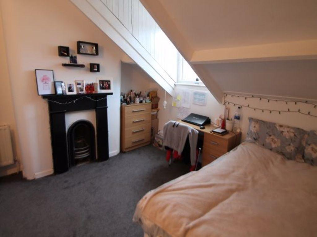 A cozy bedroom with a sloped ceiling, featuring...
