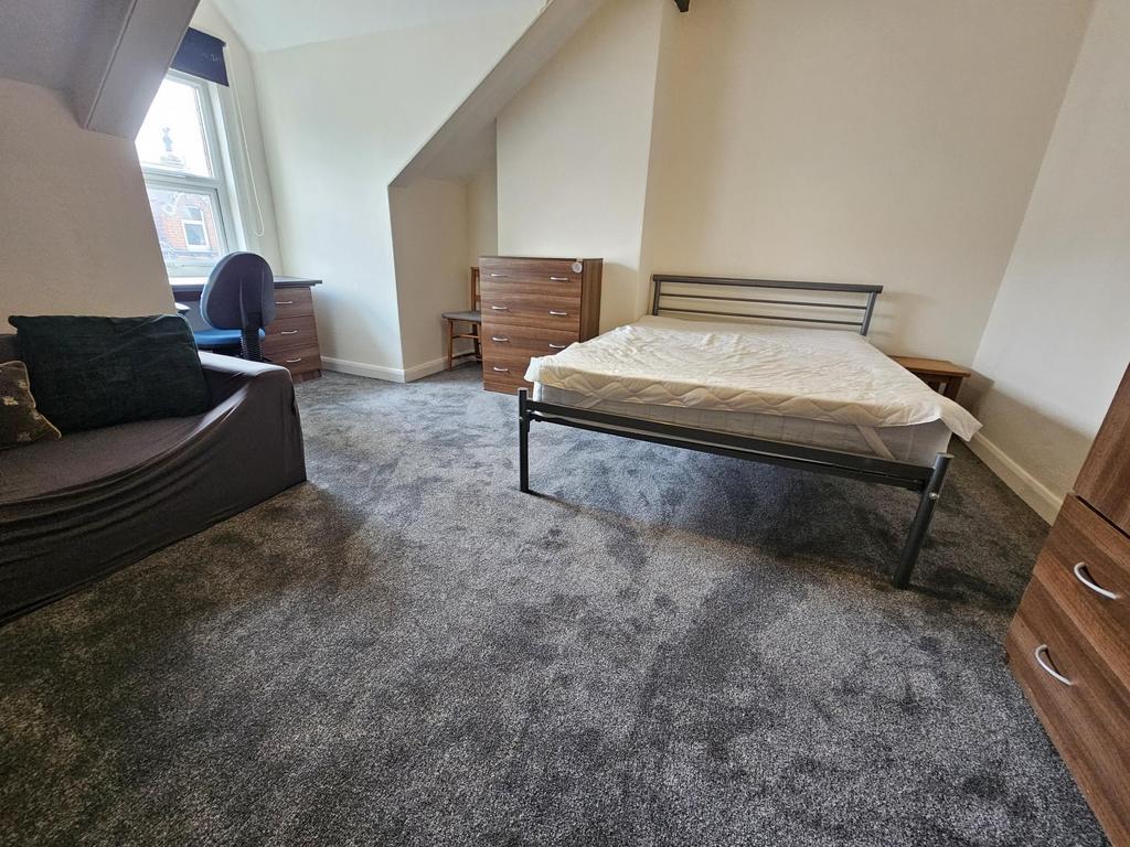 A cozy single bedroom featuring a bed, a window...