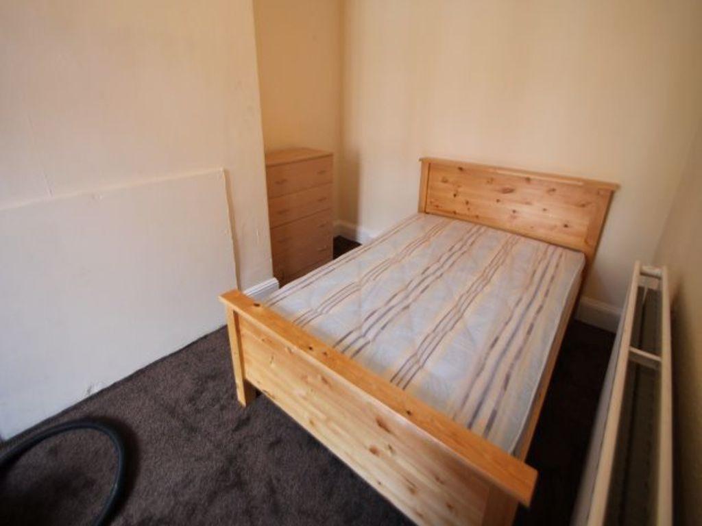 A cozy single bedroom featuring a wooden bed fr...