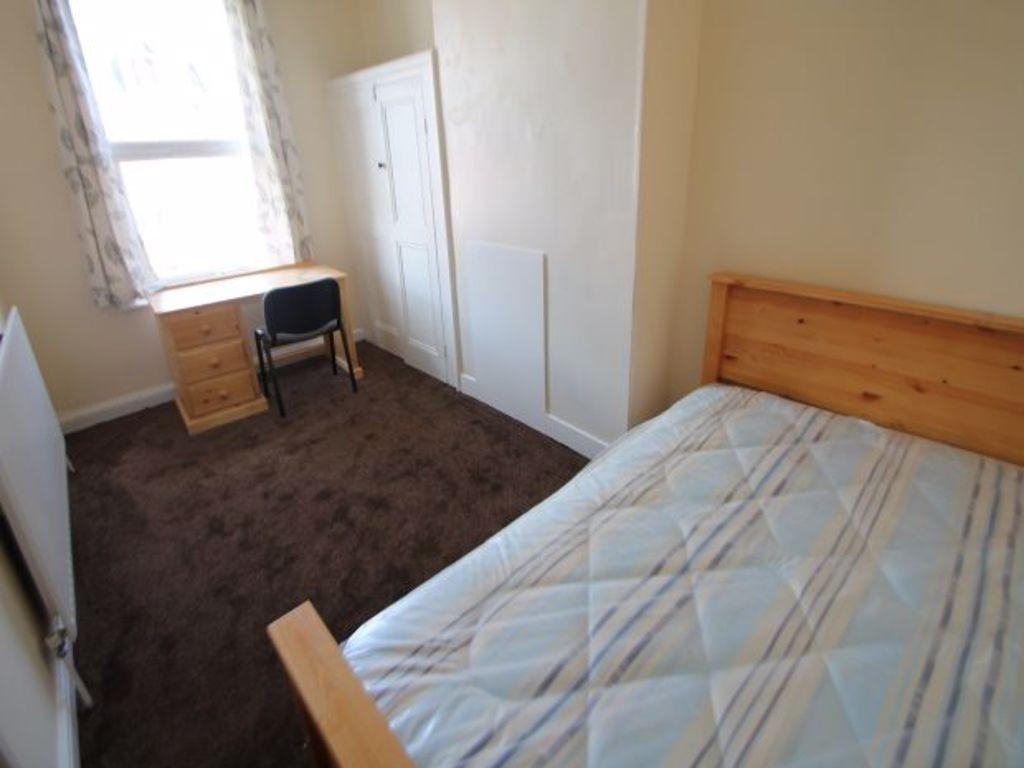 A cozy bedroom featuring a wooden bed frame wit...