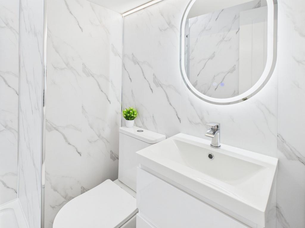 Modern bathroom with white marble walls, sleek ...