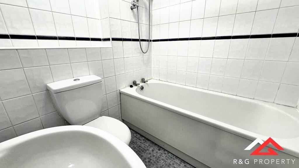 A clean and bright bathroom featuring a bathtub...