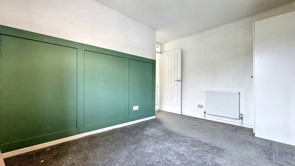 A spacious and well-lit bedroom with a large wi...