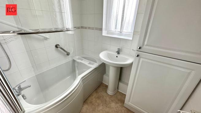 A clean and functional bathroom with a bathtub,...