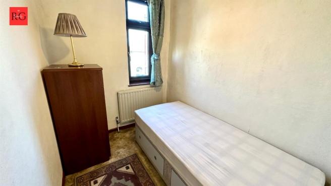 A small, tidy bedroom with minimal furnishings,...