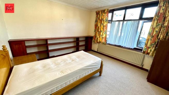 A cozy single bedroom featuring a wooden bed fr...