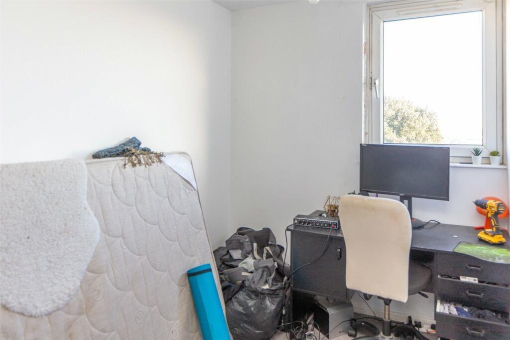 A modest bedroom featuring a bed, a window prov...