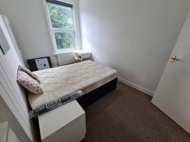 A modest, tidy bedroom with a single bed, a sma...
