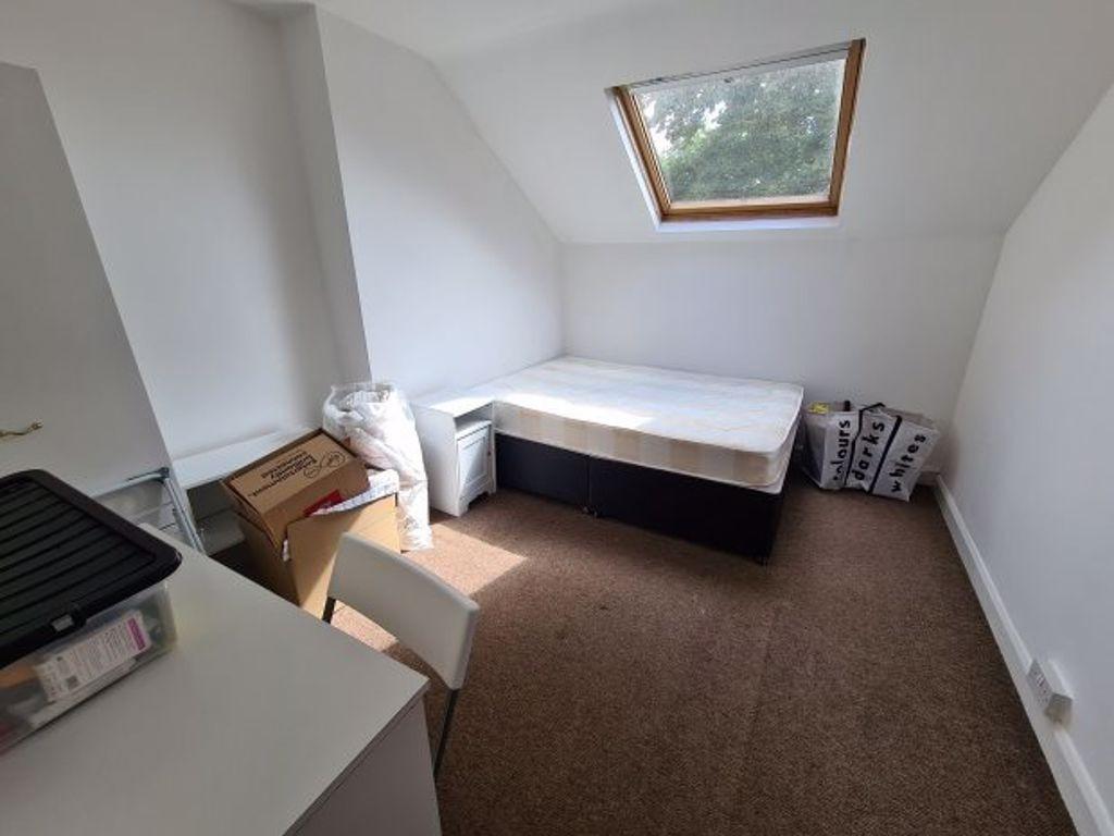 A compact single bedroom with a sloped ceiling,...