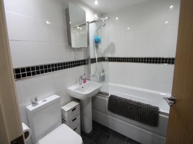 Bright and clean bathroom featuring a bathtub w...