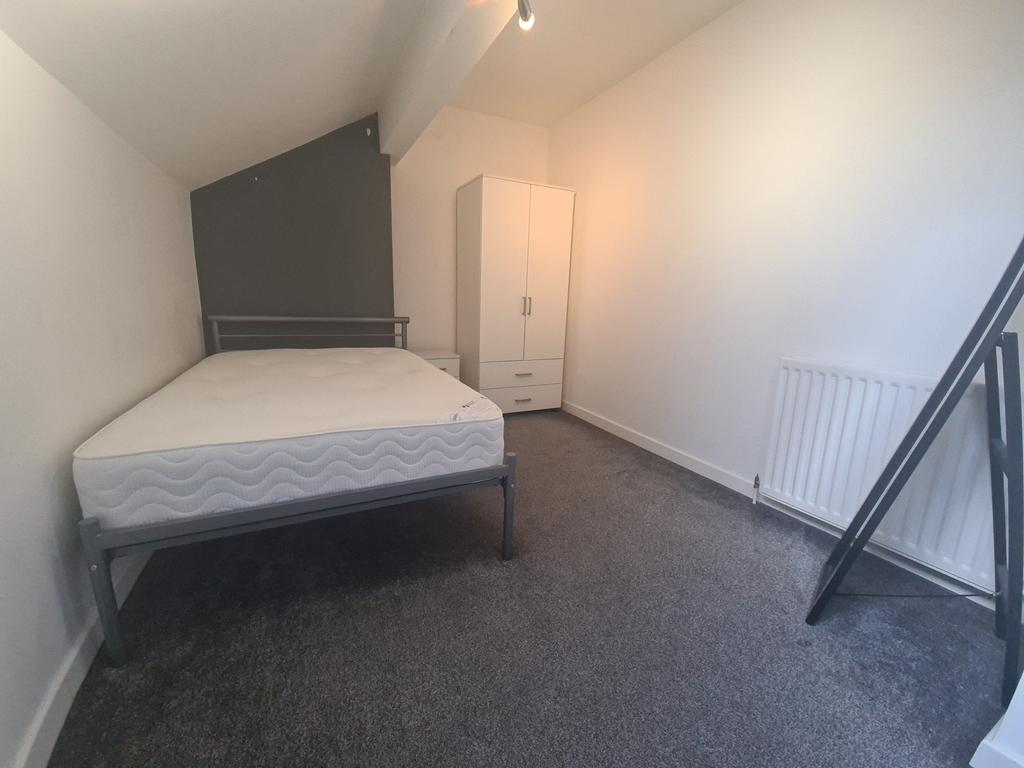 A tidy, well-lit small bedroom featuring a sing...