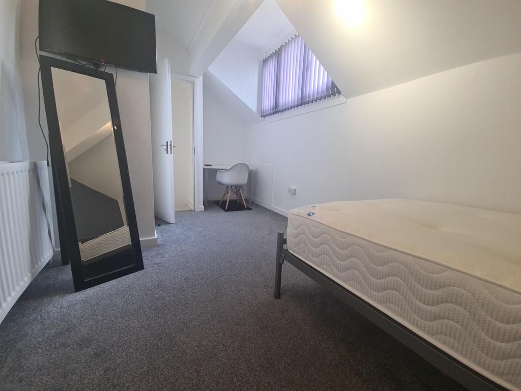 A bright and tidy single bedroom with a sloped ...