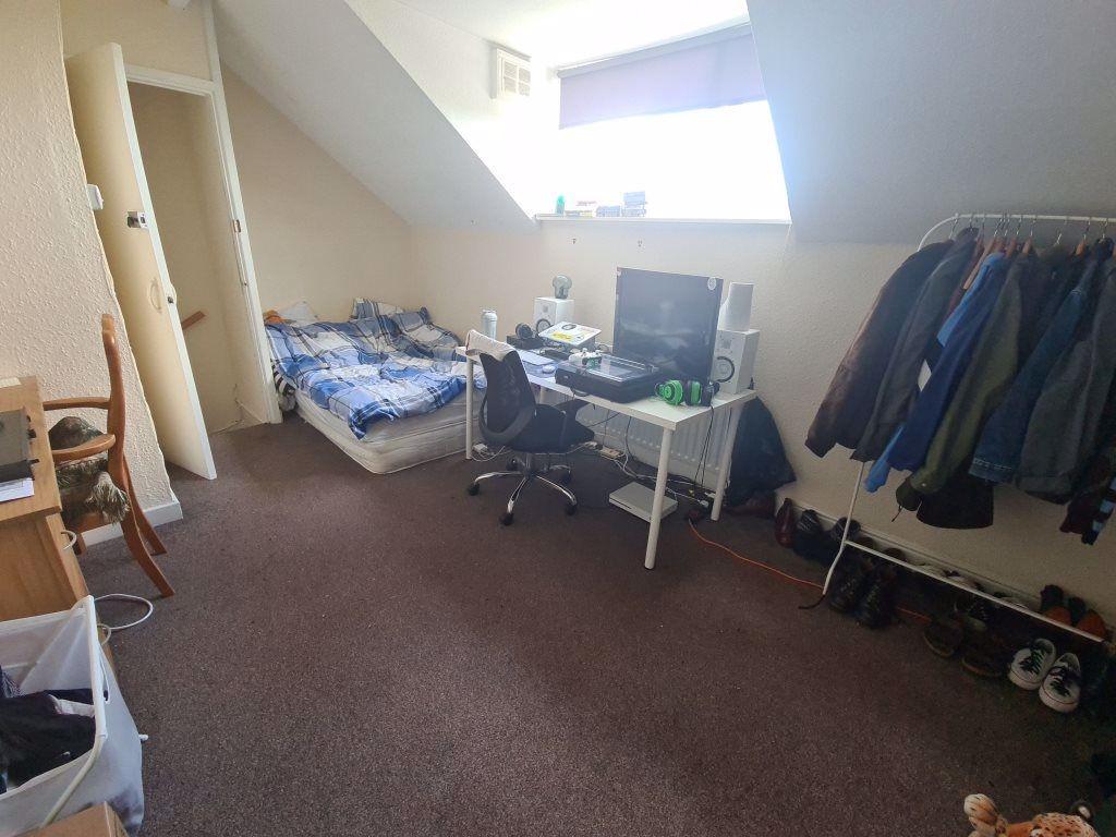 A modest bedroom with a single bed, cluttered d...