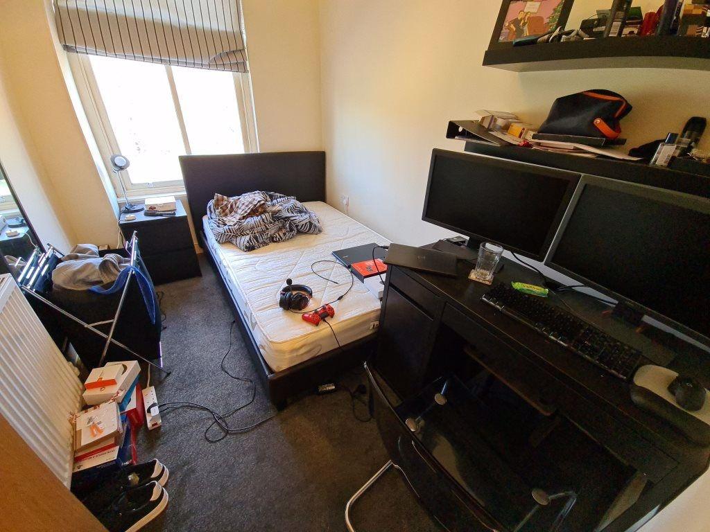 A cozy single bedroom featuring a bed, a desk w...