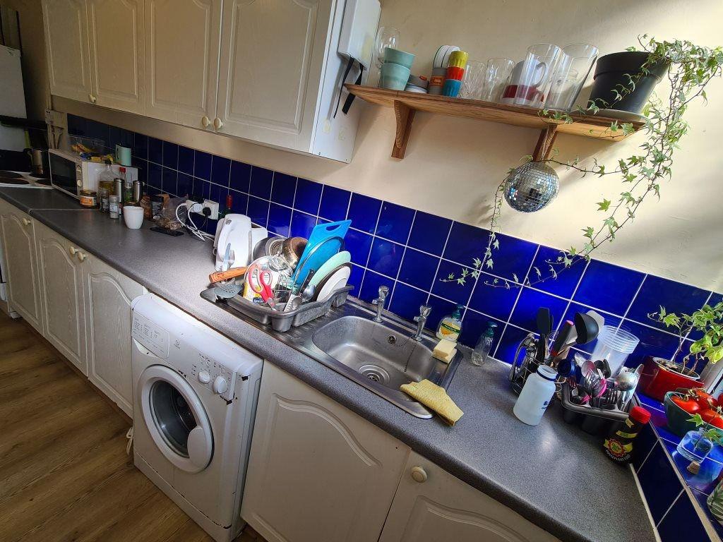A well-equipped kitchen with a blue tiled backs...