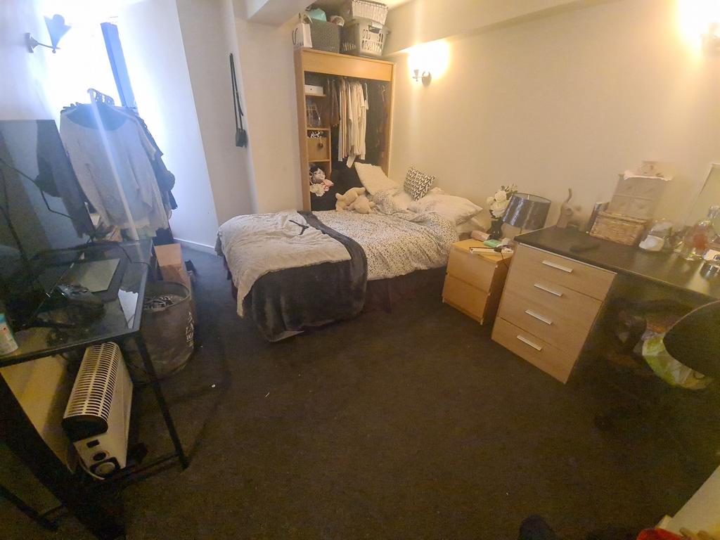 A cozy single bedroom featuring a bed, a desk, ...