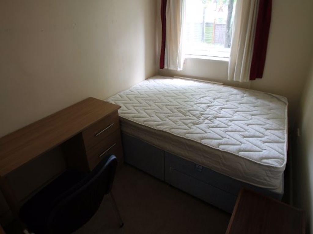 A cozy student bedroom featuring a simple bed, ...