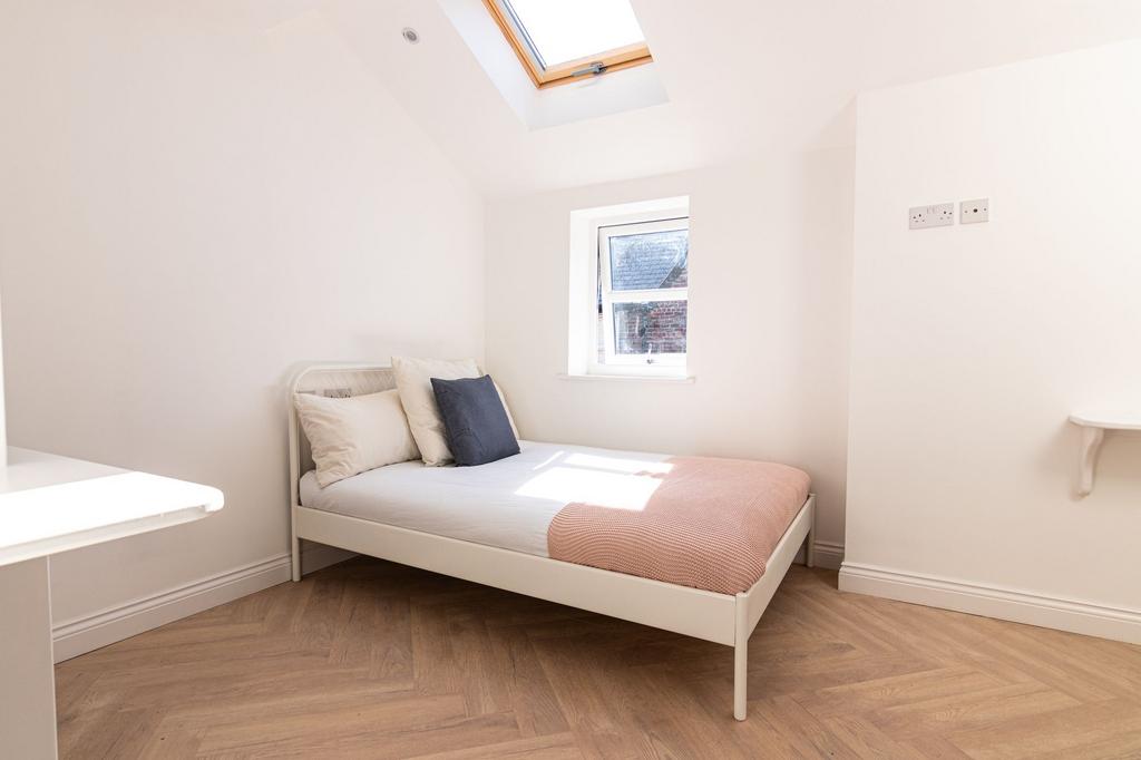 Bright and stylish bedroom featuring a clean wh...