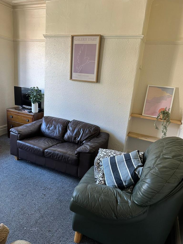 A cozy living room featuring two leather sofas,...