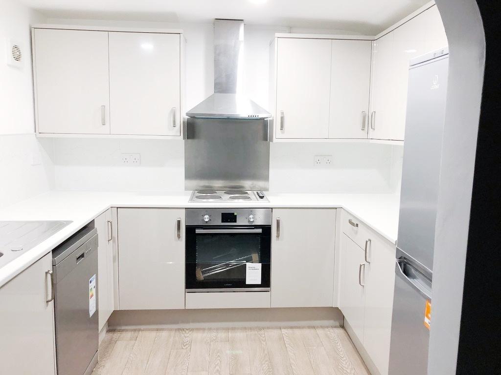 Bright modern galley-style kitchen with white c...