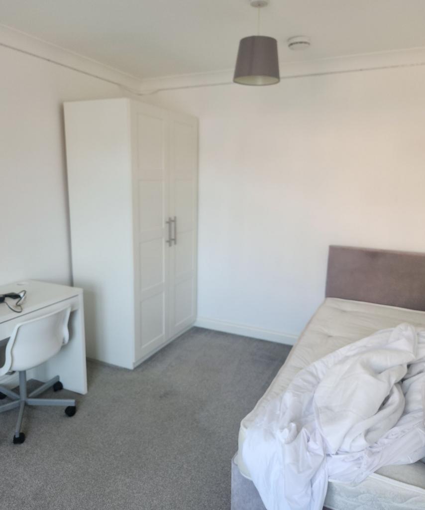 A tidy bedroom featuring a wardrobe, a bed with...