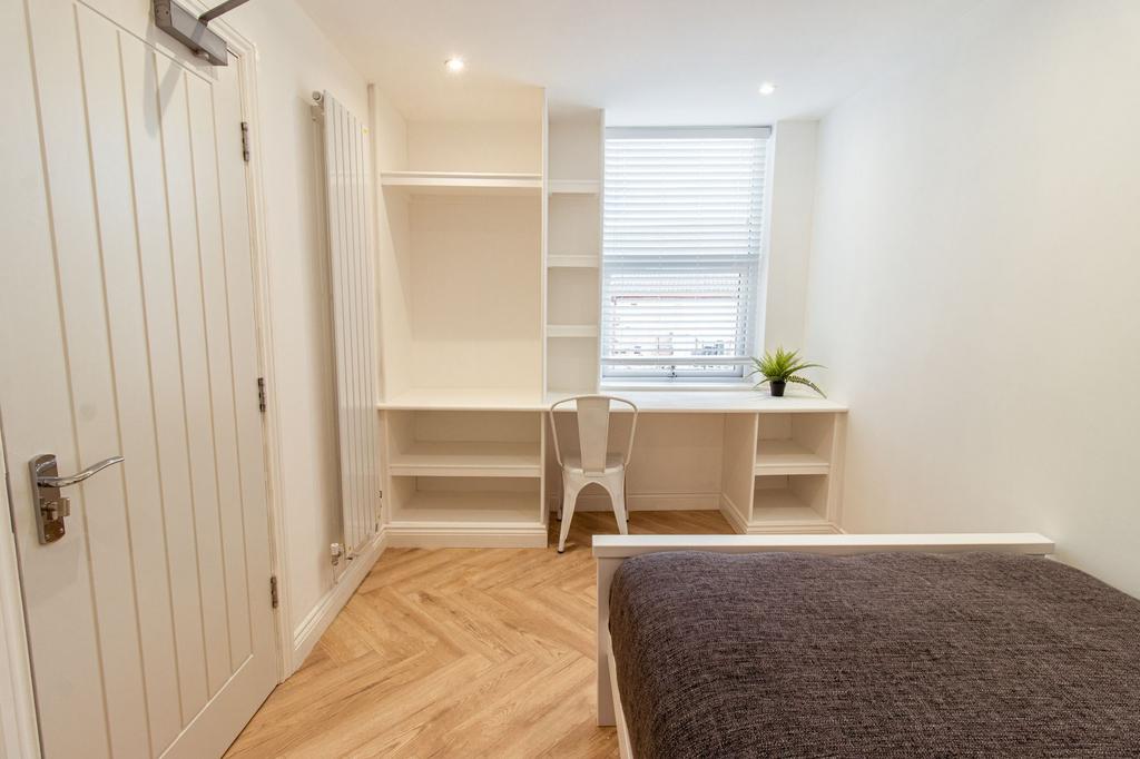 A neatly maintained student bedroom featuring a...