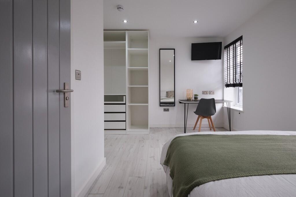 A well-maintained bedroom with a neatly made be...