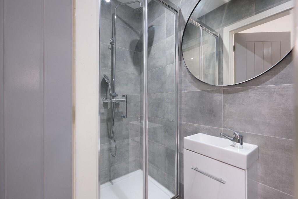 A modern, clean bathroom featuring a shower are...
