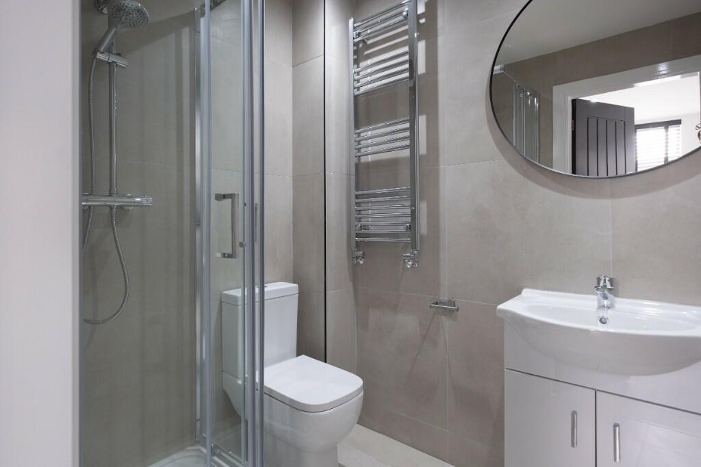 A modern bathroom suite featuring a glass-enclo...