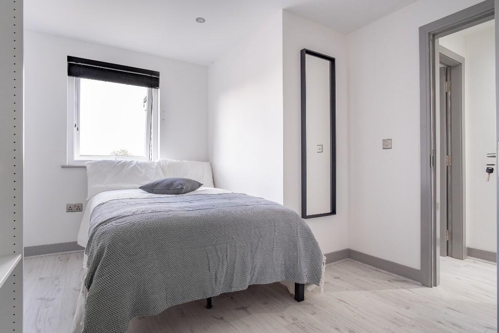 A bright and tidy bedroom featuring a comfortab...