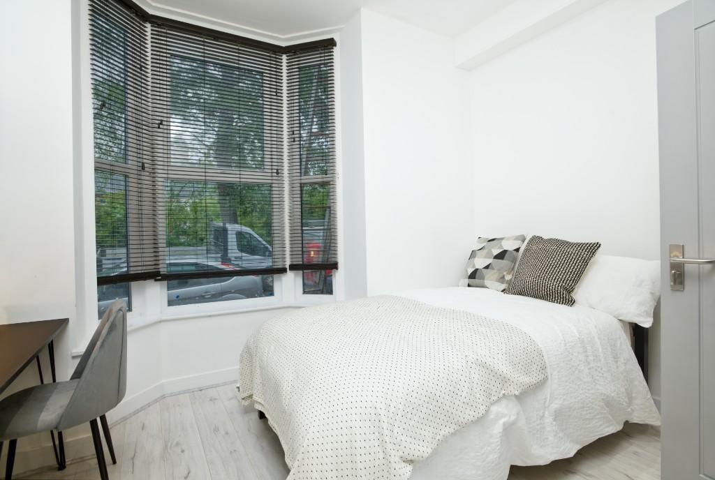 A bright, inviting master bedroom with large wi...