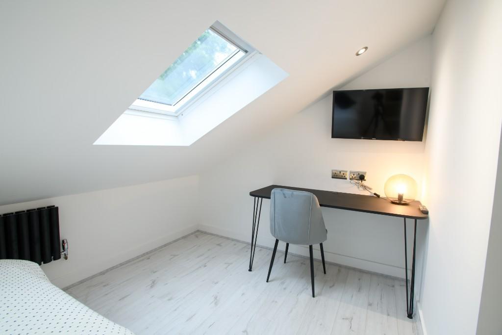 A bright and modern bedroom with a sloped ceili...