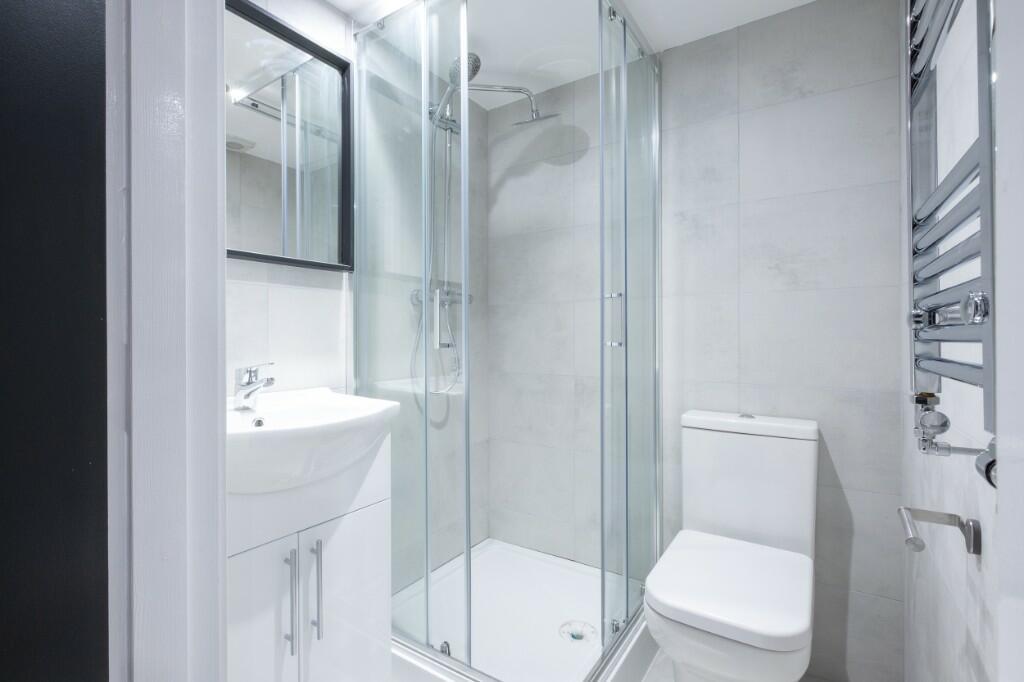 A modern, compact bathroom featuring a glass sh...