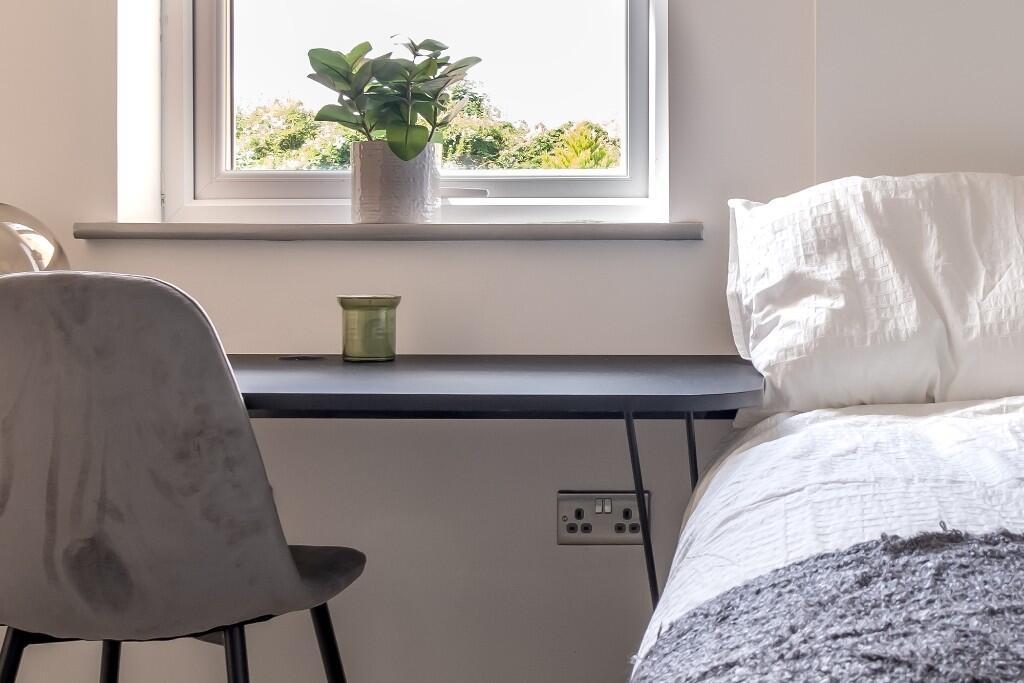 A well-lit bedroom featuring a comfortable bed ...